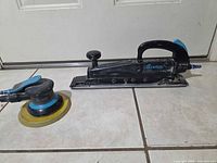 Both Baxter air sanders side by side on tile floor