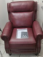 Front view of burgundy leather recliner with instructions packet on seat