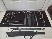 All knives laid out: fixed blades, machete, dagger, and multiple folding knives