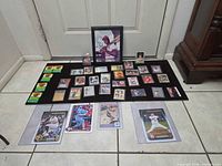 Entire lot laid out: framed Lou Brock photo, array of cards on black mat, three oversize cards below