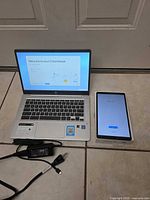 HP Chromebook and Samsung tablet side by side, both powered on with chargers visible
