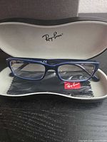 Front view of blue Ray-Ban eyeglass frames resting in open case with cloth