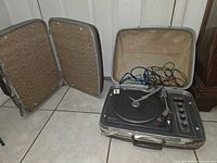Full view of open suitcase phonograph with detached speaker lids and cables