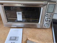 Front view of Breville Smooth Wave toaster oven with rack inside and manual in foreground