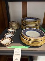Stacks of cobalt blue gilt-rim dinner and salad plates with three Imari teacups
