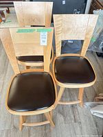 Front view of two stools showing wood finish, vinyl seats, back design