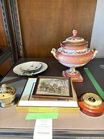 Group view of porcelain urn, two decorative plates, framed print, brass incense pot, and wooden barometer