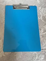 Front of blue clipboard showing surface and clip