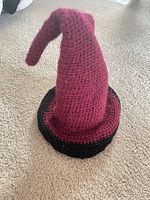 hat standing upright, burgundy cone, black brim on carpet