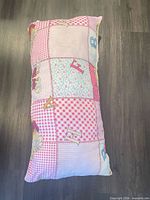 Full view of patchwork pink body pillow on floor