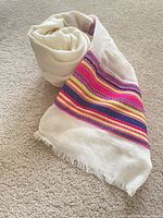 Scarf rolled showing cream fabric and multicolour stripe panel