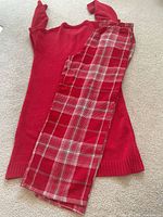 Full view of red fuzzy top and plaid pants laid flat