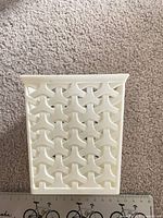 Front view of off-white plastic pencil pot, geometric cut-outs visible