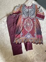 Full view of tunic and bottoms laid out on floor