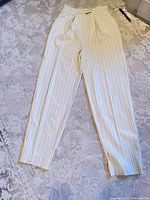 Full front view of cream pinstripe trousers laid flat