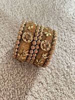 Stack of six gold-tone bangles on carpet