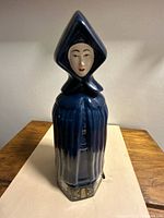 Front view of dark blue ceramic Mulher do Capote bottle