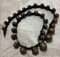 Coiled leather strap displaying all attached brass sleigh bells