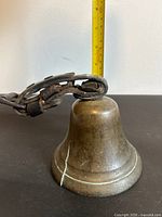 Side view showing bell height against tape, leather strap looped over top