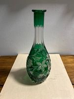 Full front view showing green cut-to-clear crystal bottle, elongated neck, grape and floral motifs