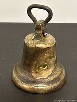 Side view of brass bell showing patina and iron loop