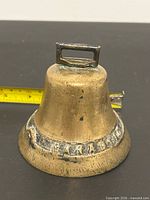 Oblique view of brass bell showing CANADA lettering and overall form
