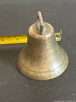 Side view of brass cowbell showing patina and handle