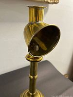 Close-up of detachable shade/snuffer showing interior mechanism on brass candlestick