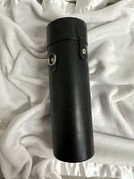Full view of cylindrical black leather case upright