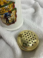 Shaker body partial view with removed brass lid showing perforations