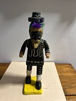 Front view of wooden dancer figurine showing mask, feathers and painted details