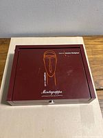 Closed burgundy lacquer Montegrappa Modigliani box showing exterior artwork and logo