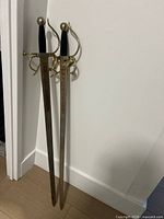 Full view of both decorative swords leaning against wall