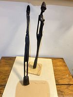 Full view of both wooden figurines standing on surface