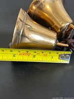 Two brass bells side by side next to tape showing 2.5 in diameter