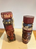Front view of both wooden head figurines standing upright