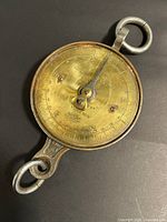 Front view of brass dial showing graduations and pointer