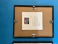 Back view of one frame showing hanging hardware and artist information sheet