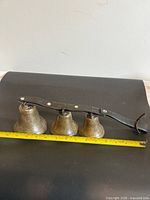 Full view of three cowbells on leather strap with measuring tape