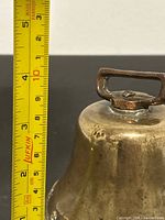 Bell with tape measure showing about 3.5 in height