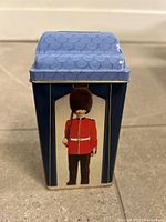 Front view showing British guard graphic on blue tin bank