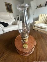 Full view of copper and brass kerosene lamp with glass chimney on table