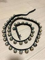 Coiled leather strap with numerous brass bells visible