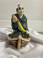 Front view of ceramic fisherman decanter seated in boat holding fish