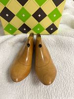 pair of wooden lasts standing toe-forward in front of argyle box