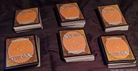 Six stacks of Magic: The Gathering cards laid out on cloth surface