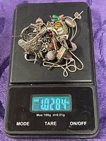 Pile of assorted sterling earrings on digital scale showing 1.02 oz