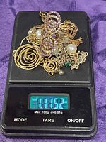 All jewelry pieces on digital scale displaying 1.11 oz