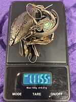 Pile of sterling earrings on scale reading 1.1155 oz