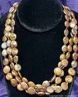 Front view of triple-strand chocolate brown button pearl necklace on display bust
